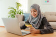 Muslim young women wear hijab are buying online with  credit card on laptop