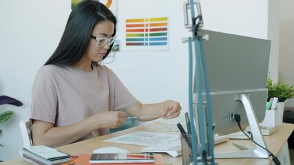 Slow motion portrait of Asian woman application developer designing app interface working in office alone using computer. People and technology concept.