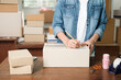 © ijeab - Online small business owner writing address on parcel box.