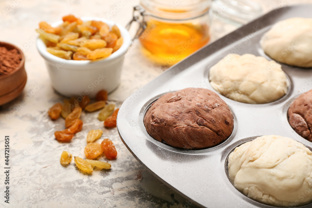 Baking tin with raw muffins and ingredients on light background