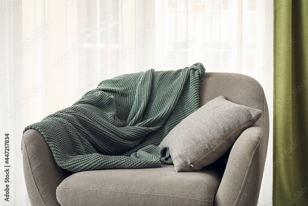 Comfortable armchair near light curtains in room
