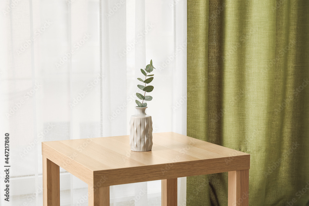 Table with vase near light curtains in room - obrazy, fototapety, plakaty 