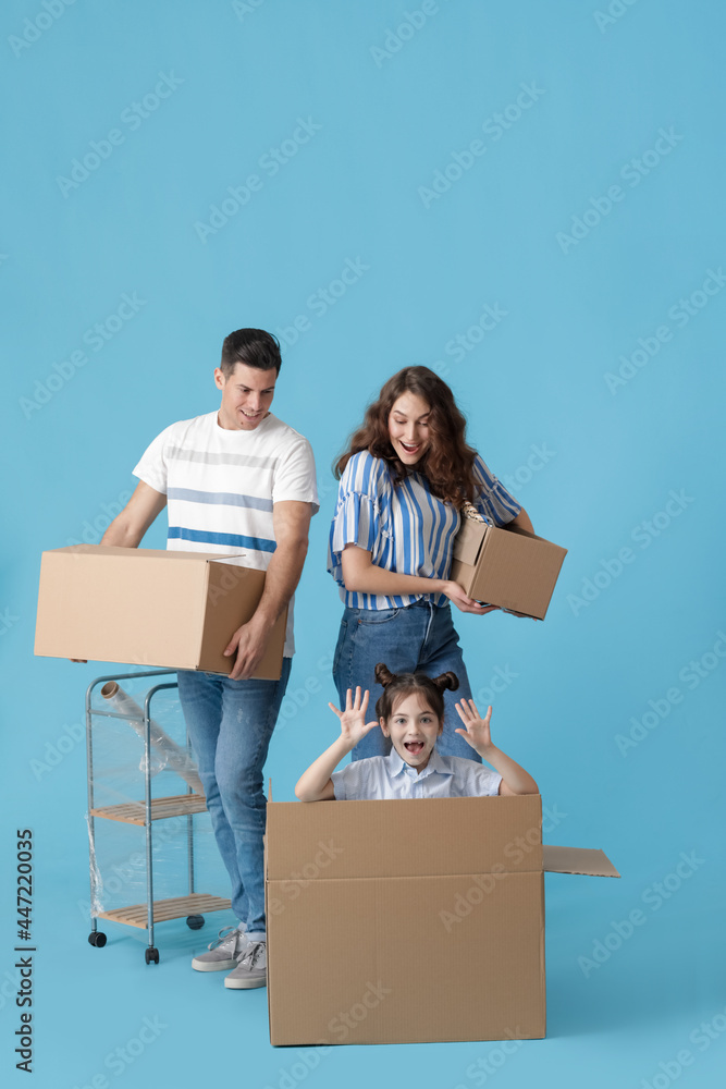 Happy family with moving boxes on color background