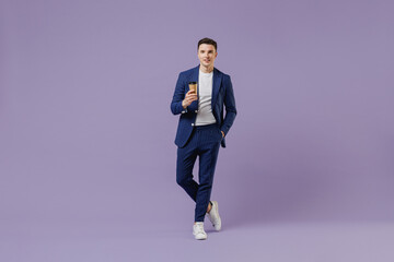 Full size young successful employee business man lawyer 20 wear formal blue suit white t-shirt hold takeaway delivery craft paper brown cup coffee isolated on pastel purple background studio portrait