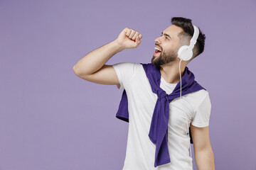 Wall Mural - Side view profile young brunet man 20s wear white t-shirt purple shirt headphones on head keep eyes closed sing isolated on pastel violet background studio portrait. People emotions lifestyle concept