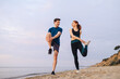 © ViDi Studio - Full body couple young two friends sporty sportswoman sportsman woman man in sport clothes warm up training run do exercise on sand sea ocean beach outdoor jog on seaside in summer day cloudy morning.