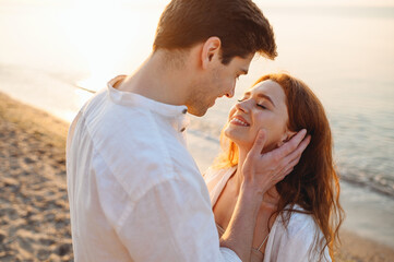 Side view happy young couple two friend family man woman in white clothes boyfriend hug girlfriend hold face enjoy together at sunrise over sea beach ocean outside seaside in summer day sunset evening