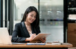 © NAMPIX - Businesswoman working on tablet and laptop computer while sitting at her office desk.