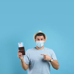 Poster - Male tourist in protective mask holding passport with ticket on turquoise background