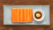 imitation crab sticks with wasabi and shoyu soy sauce in ceramic plate on rustic natural wood texture background, top view
