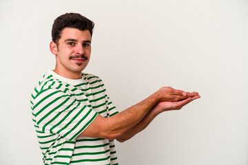 Young caucasian man isolated on white background holding a copy space on a palm.