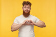 © timtimphoto - indoor shot of joyful attractive young man, wears blank t-shirt, shows heart with his arms, love gesture. isolated over yellow background