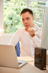 Wall Mural - serious young entrepreneur working at office desk and recording voice message for coworker