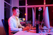 Positive software developer working on computer at office table, pink neon light