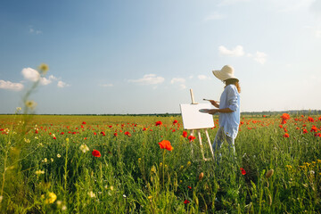 Woman painting on easel in beautiful poppy field