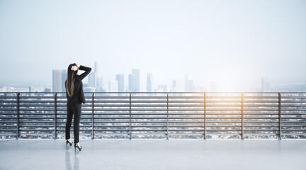 Canvas Print - Businesswoman on concrete balcony looking into the distance at city with mock up place. Success and future concept.