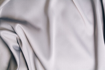 Textured backdrop of gray silk or satin. Shiny waves of textiles. Copy space