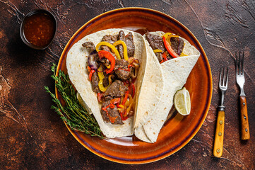 Sticker - Fajitas Tortilla wraps with beef meat steak stripes, sweet pepper and onions. Dark Wooden background. Top view