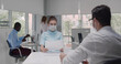 © TommyStockProject - Female employer wearing face mask holding cv listening male candidate at job interview