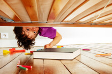 Boy Finds Book Under The Bed Leaning Down