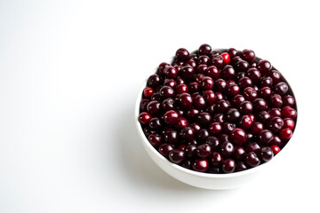 Dark red cherry in a white cup on a white background.
