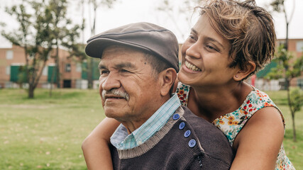 older man being hugged by his middle-aged daughter in the park