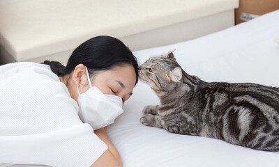 An adorable cat is kissing its owner's forehead to show affection and encouragement. women wearing hygienic mask to prevent the virus Coronavirus at Stay home in quarantine. Home Isolation