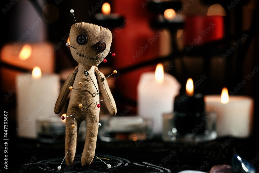 Voodoo doll pierced with pins on table in dark room, space for text. Curse ceremony - obrazy, fototapety, plakaty 