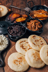 Wall Mural - Table served with Venezuelan breakfast, arepas with different types of fillings such as caraotas, carne mechada, pernil , fried plantain and cheese