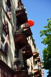 Sonnenschirm in leuchtendem Orange im Sommer bei blauem Himmel und Sonnenschein auf dem Balkon eines Altbau in einer grünen Allee im Nordend von Frankfurt am Main in Hessen