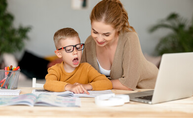 Wall Mural - Happy mother supporting son during online studies