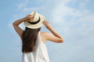 Poster - Beautiful young woman wearing straw hat outdoors, back view. Stylish headdress