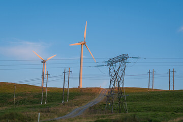 Wind turbines with power lines in the foreground in evening light. UK