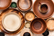 Many different ceramic and wooden plates and bowls on a beige background top view. Flat lay. Background from empty plates and bowls. Various empty dishes.