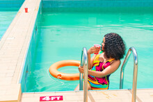 Beautiful African Lady Sipping Drink From A Cup In A Pool
