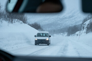 van driving on highway road with snow covered in blizzard