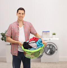 Canvas Print - Smiling young man carrying a laundry basket