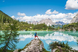 Fototapeta  - Backpacker with backpack enjoying the turquoise Lago di Sorapiss 1,925m altitude (mountain lake) view as he has mountain walk in Dolomite Mountains, Italy. Active people in nature concept.