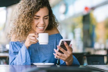 Latin woman using a mobile phone at a coffee shop.