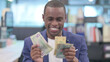 © stockbakers - Portrait of Young African Businessman Counting Dollars