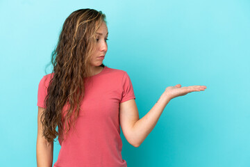 Young caucasian woman isolated on blue background holding copyspace with doubts