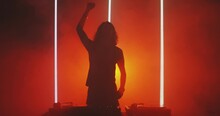 Hot dj rave. Silhouette of dancing deejay young guy rocking party up in red light in smoke in nightclub