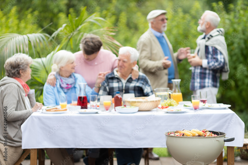 Happy senior friends during party at beautiful garden of suburban villa