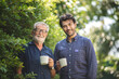 © chokniti - adult son and elderly senior father talking together and holding coffee cup in the garden, happy morning lifestyle of man generation family, love day at home