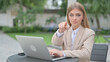 © stockbakers - Businesswoman with Laptop Pointing at Camera in Outdoor Cafe