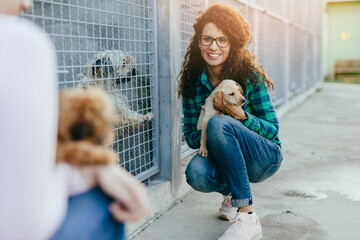 Two young adult women adopting beautiful dogs at animal shelter.