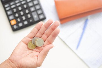 Wall Mural - Thai coin on palm up with calculator pen wallet and document blur. Recording of cash expenditures account of family in home. planing earn investment and saving finance money future for 2022 new year.