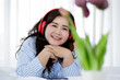 © Bangkok Click Studio - Asian young happy calm fat overweight woman lay down with happy smiling deep emotion peacefully while listening to music from big red earphones use playlist from black tablet at home in bedroom