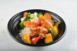 hawaiian sweet & sour grilled chicken pineapple rice bowl with fried vegetable salad in black bowl in white marble healthy poke bowl menu