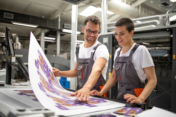 Graphic engineers or workers checking imprint quality in modern print shop.